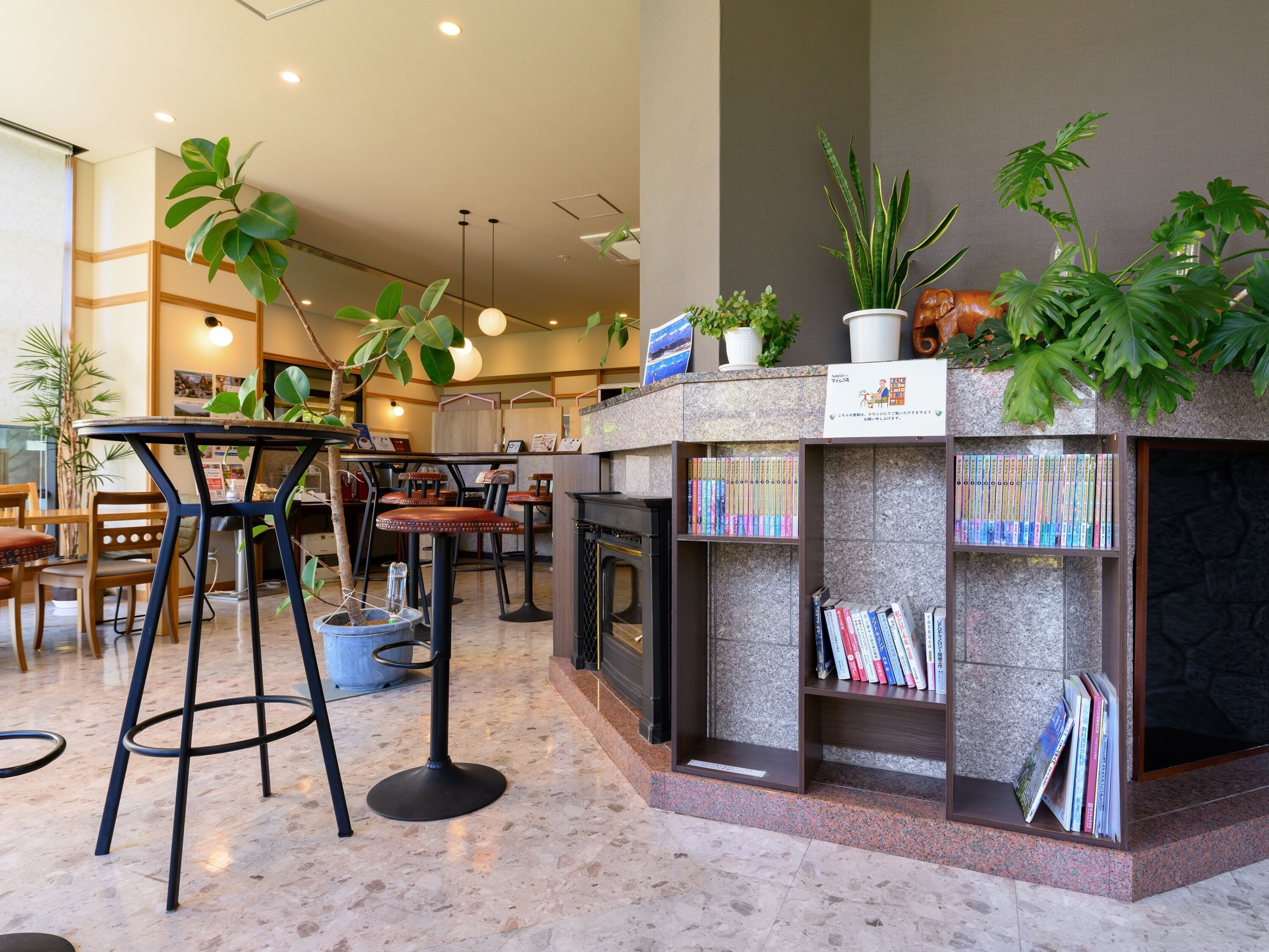 A modern indoor space with a bar area, seating, and a bookshelf with books.