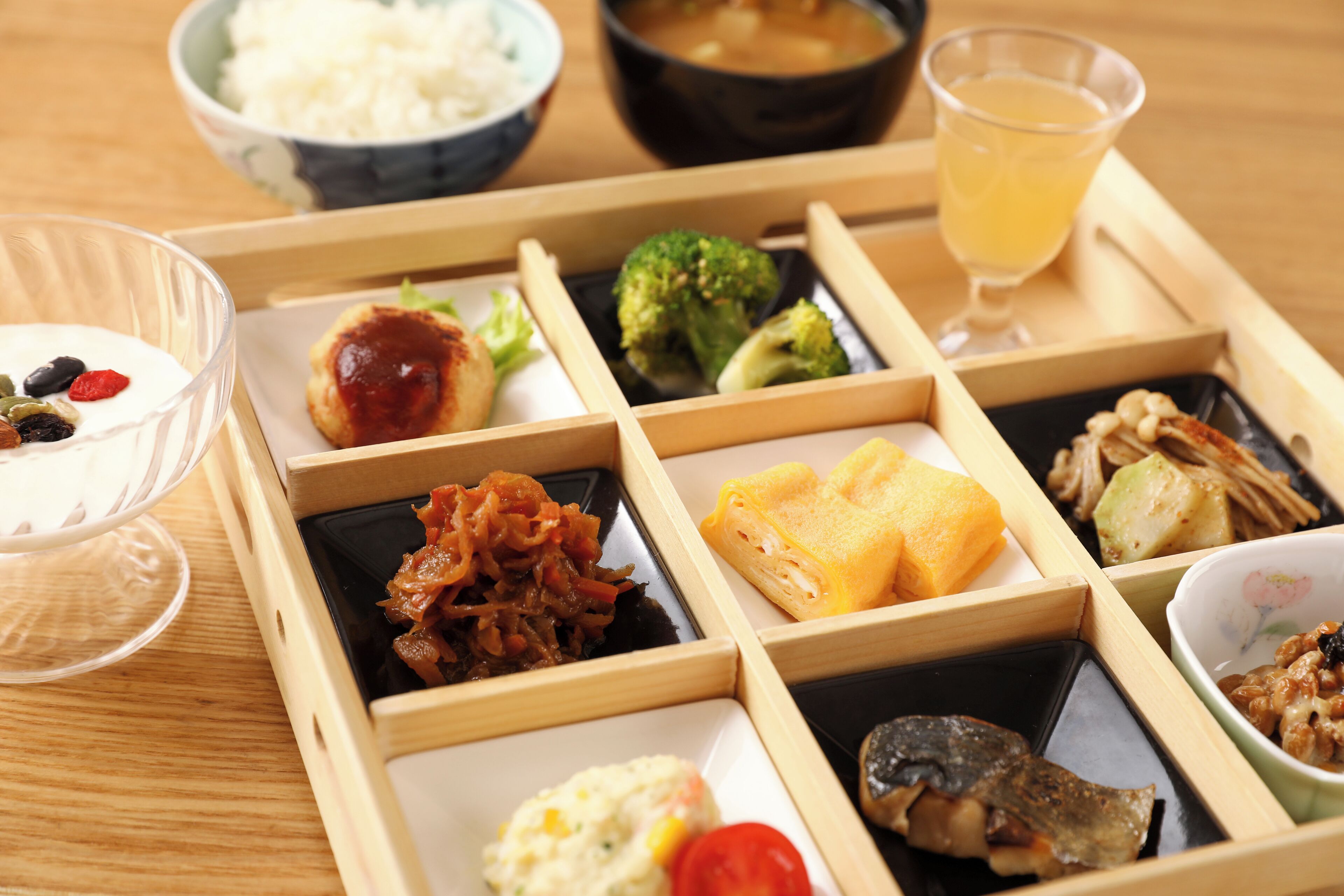 A traditional Japanese bento box with various food items, including rice, vegetables, and meat, arranged neatly in compartments.