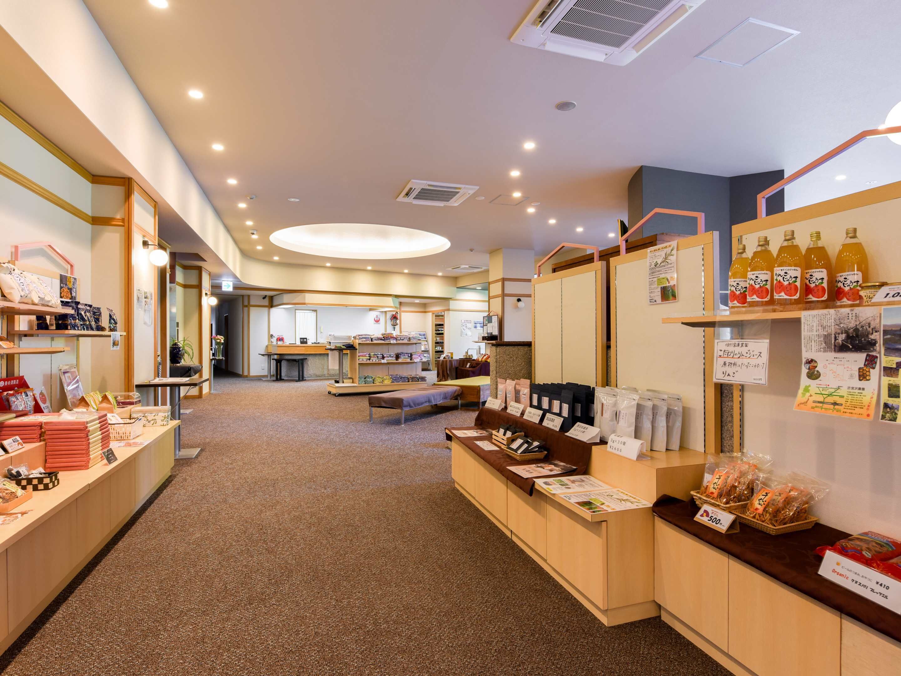 A well-lit indoor space with wooden counters displaying various products, a seating area in the background, and a ceiling with recessed lighting.