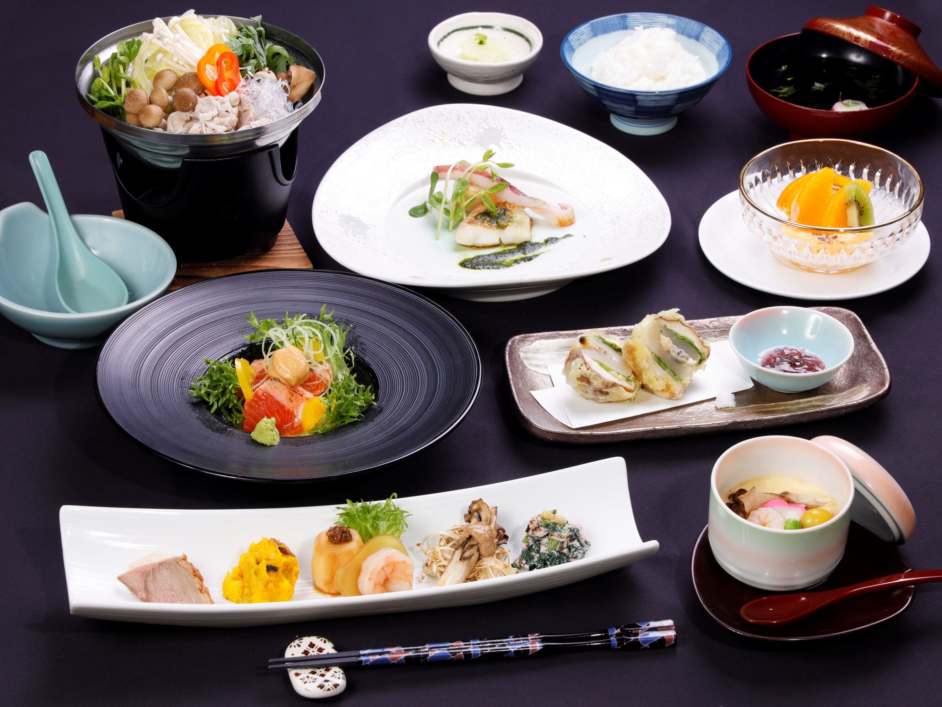 Variedad de platos japoneses, incluyendo sushi, sashimi y tempura, dispuestos en platos y cuencos.