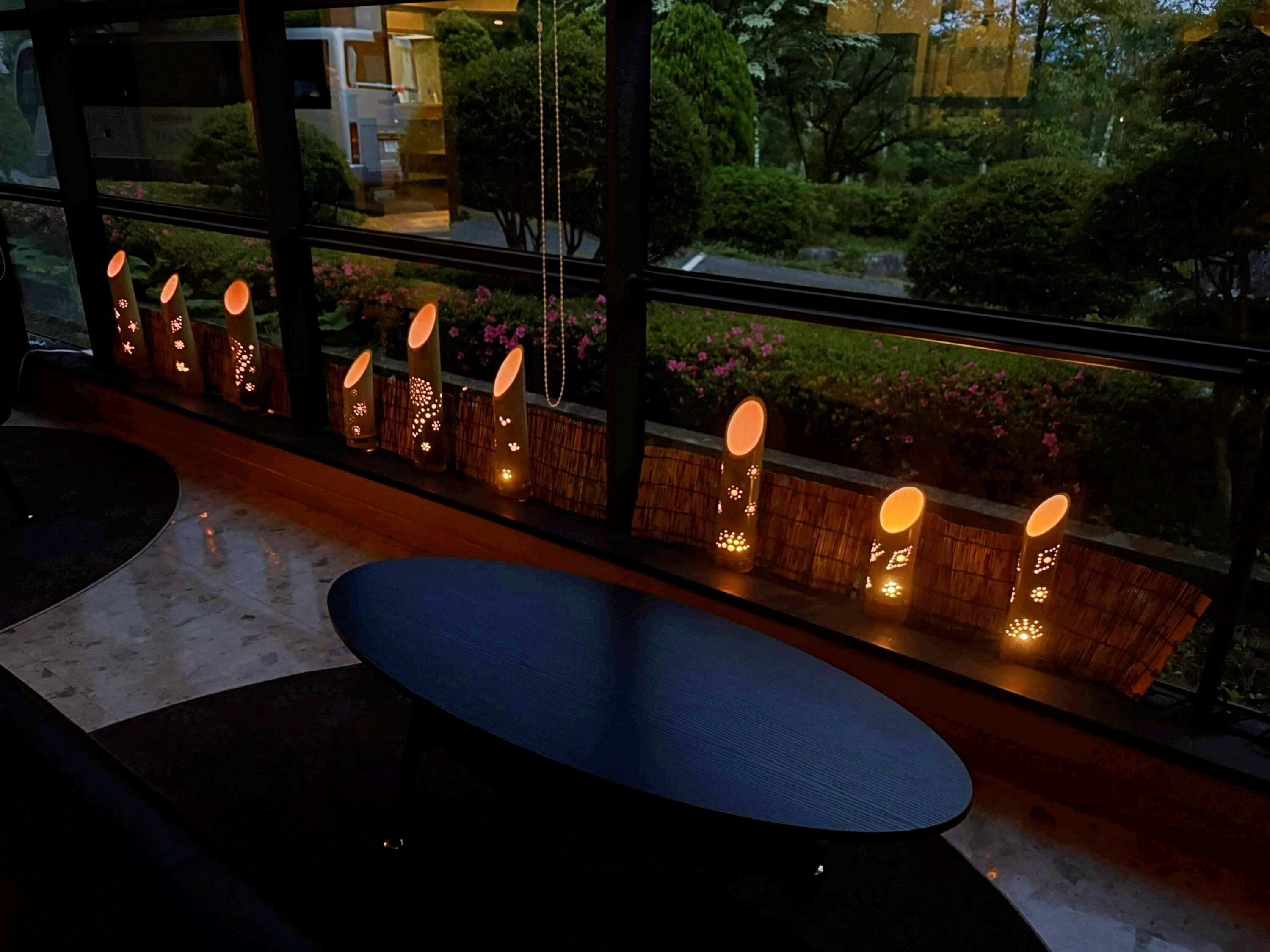 Un interior moderno con una zona de estar, una ventana con luces decorativas y vistas a la vegetación.