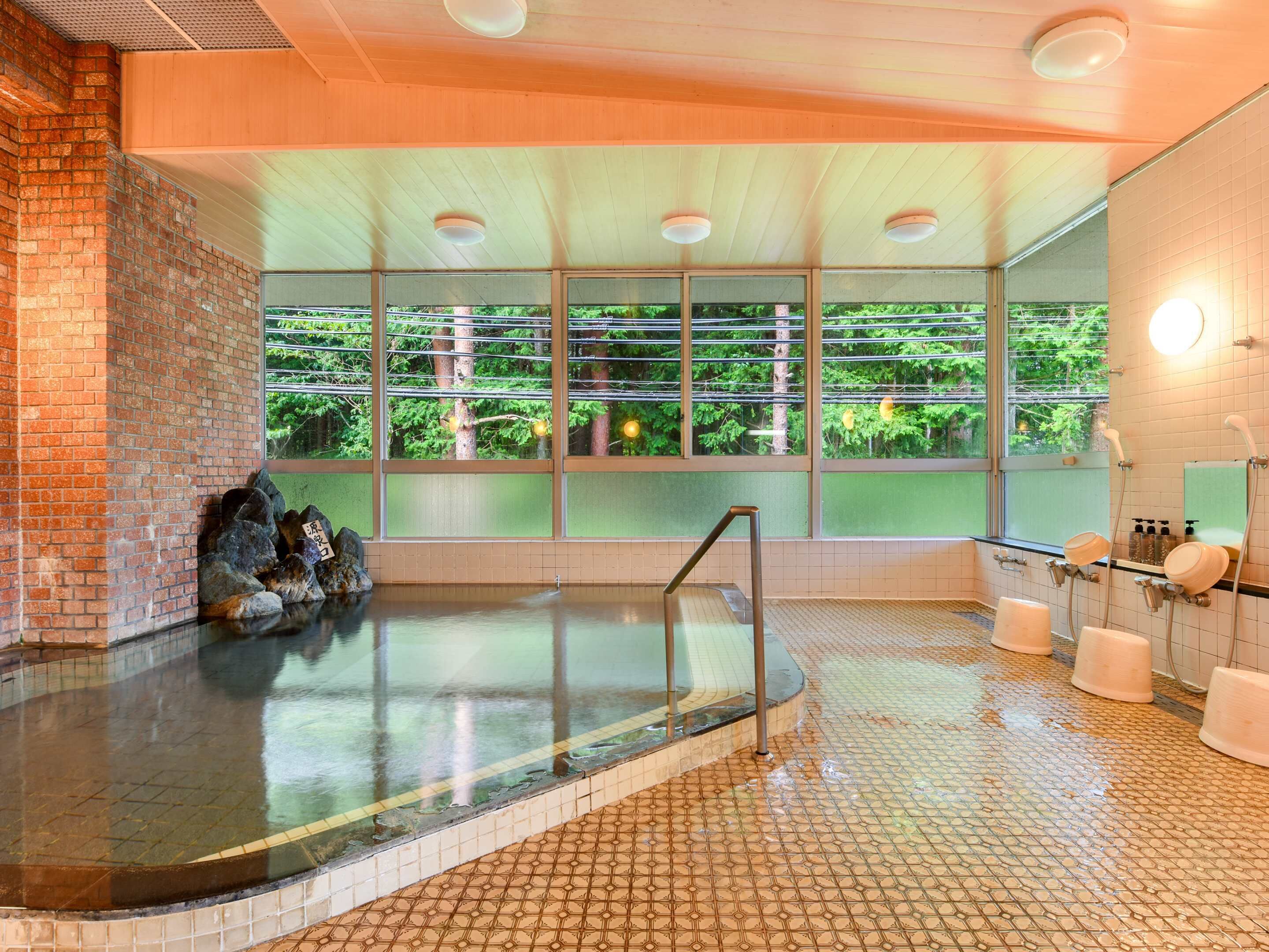 A modern indoor pool with a glass wall, a brick wall, and a tiled floor.