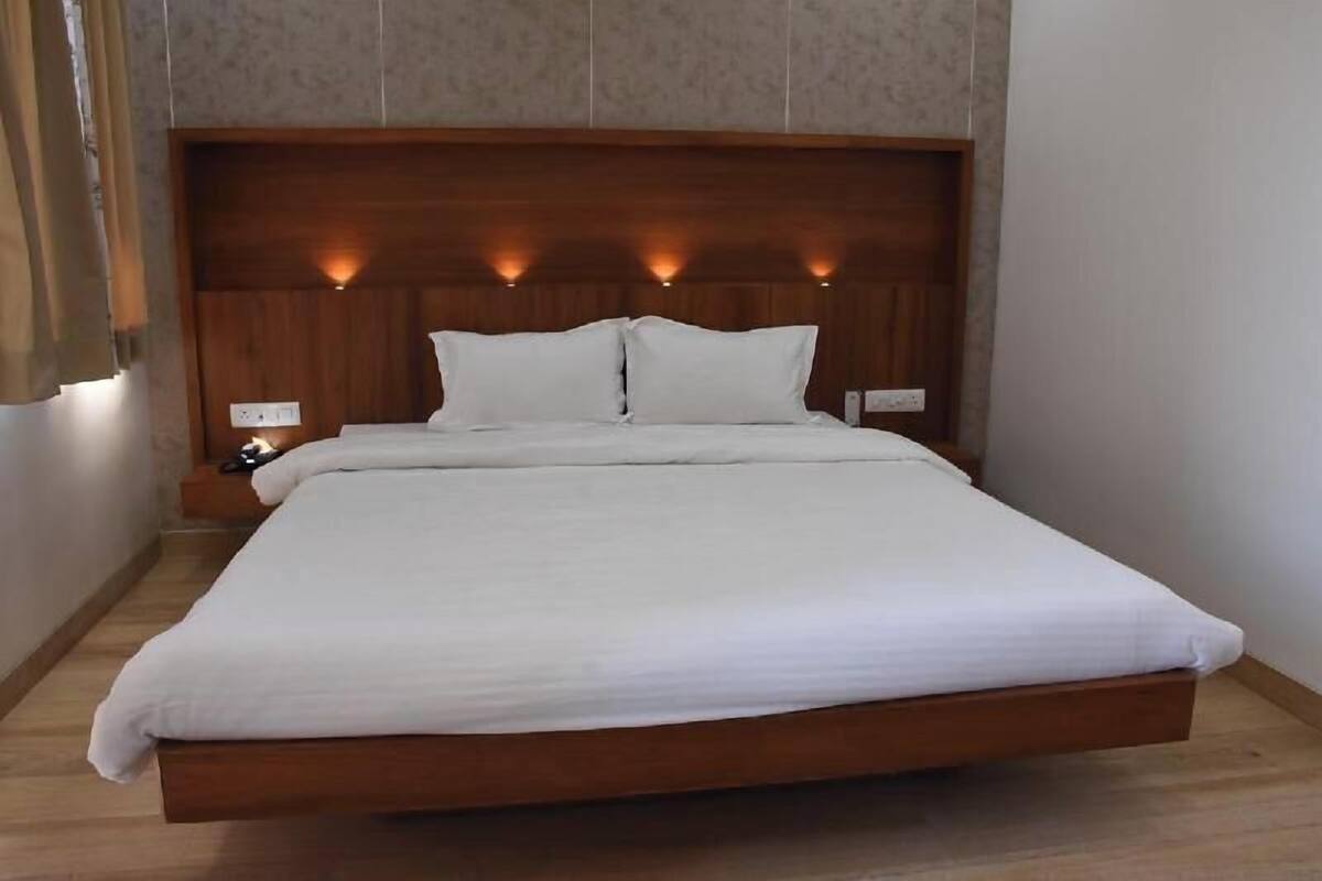 Ein Bett mit hölzernem Kopfteil, weißer Bettwäsche und Nachttischlampen.