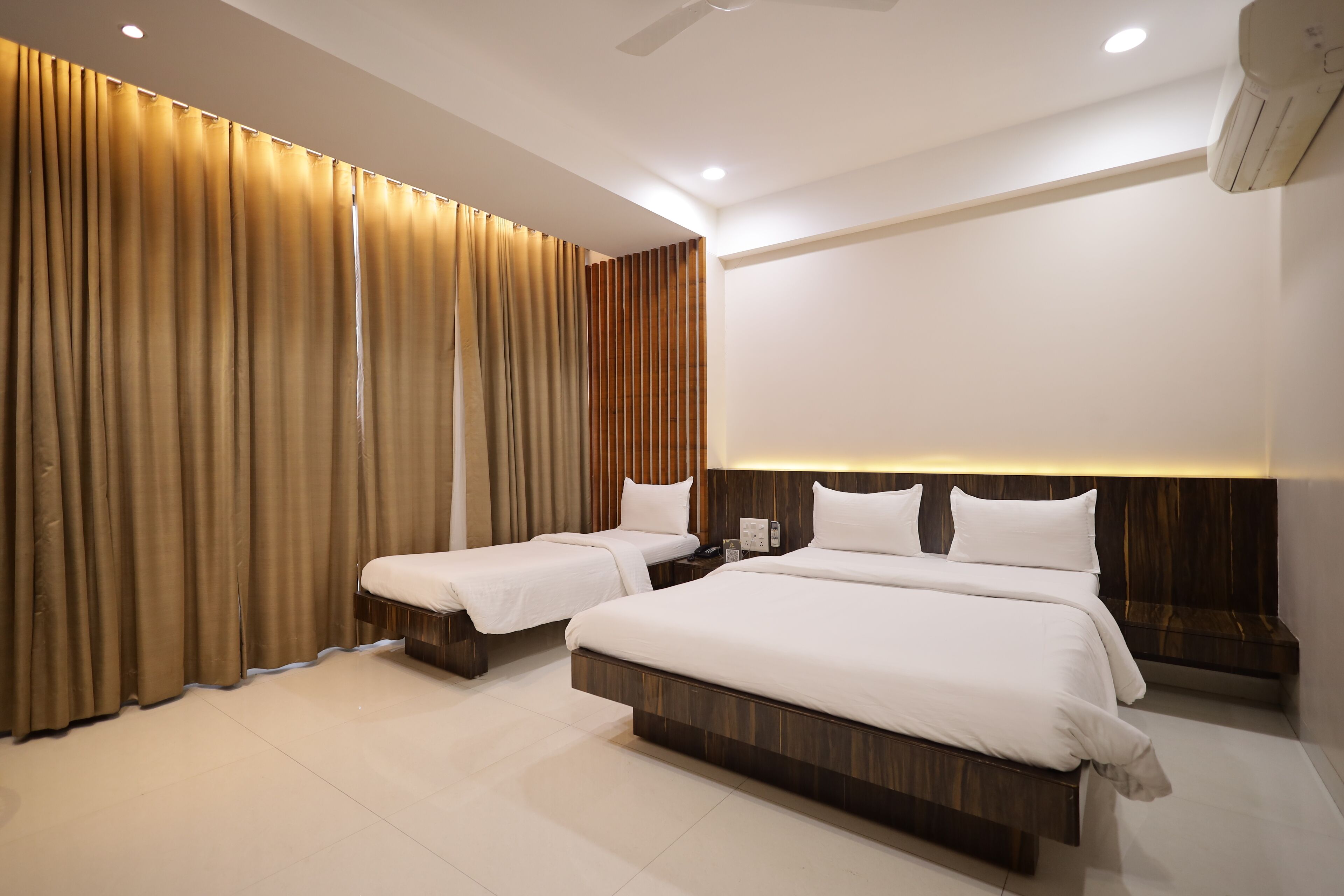 A modern hotel room with two beds, a large window, and a wooden headboard.