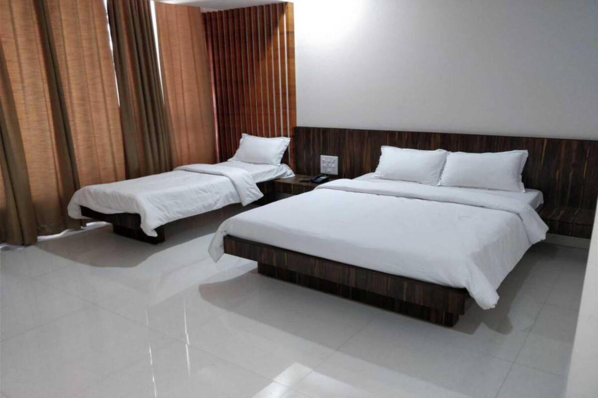 Ein Hotelzimmer mit zwei Einzelbetten und einem Doppelbett, alle mit weißen Laken.