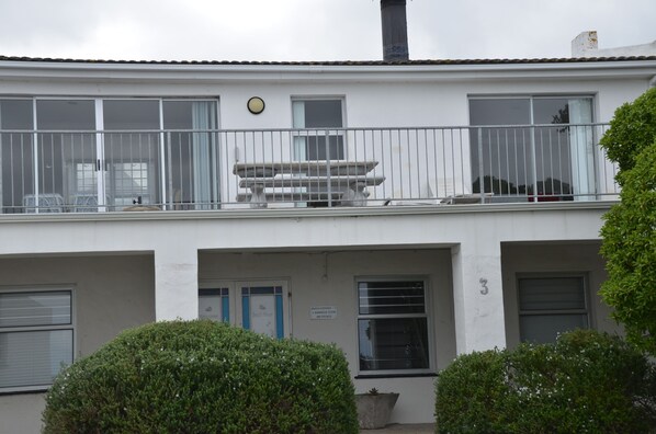 Een gebouw met een balkon, een bankje en een bloempot.