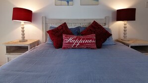 Ein Schlafzimmer mit einem Bett, zwei Nachttischen, zwei Lampen und zwei Wandbildern.