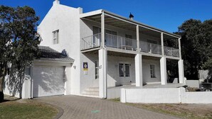 Ein zweistöckiges, weißes Gebäude mit Balkon und Garage unter blauem Himmel.