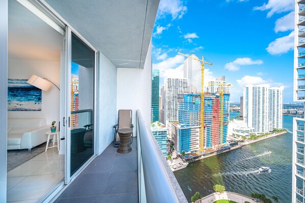 A balcony with a view of a river and high-rise buildings, including a construction site.