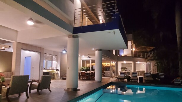 Un espace piscine intérieur moderne, doté d’un coin repas et d’un escalier menant à un niveau supérieur.
