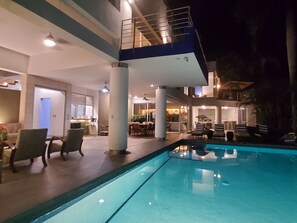 Uma área interna de piscina moderna, com espaço para refeições e escadaria que dá acesso a um andar superior.