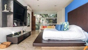 Une chambre moderne avec un lit, un téléviseur fixé au mur et une vue sur l’extérieur.