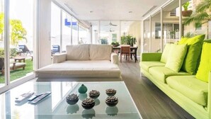 Un salon moderne avec une table basse en verre, un canapé beige et un canapé vert.