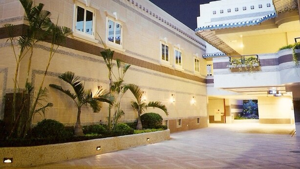 Un hotel con patio, palmeras y una entrada bien iluminada.
