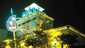 Un hotel con un letrero de neón, varios pisos y un estacionamiento.