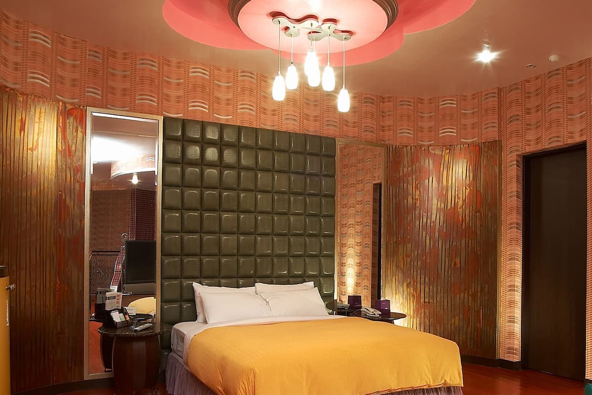 A hotel room with a large bed, a mirror, a vanity, and a wardrobe.