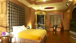 Ein Hotelzimmer mit einem großen Bett, einem Schminktisch mit Spiegel, einem Fernseher und Holzboden.