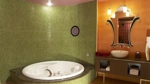 Ein Badezimmer mit einer großzügigen, freistehenden Badewanne, einem Waschtisch mit Spüle und einem beleuchteten Spiegel.