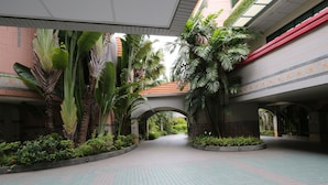 Ein geräumiger Innenhof mit Fliesenboden, umgeben von üppiger Vegetation und architektonischen Bögen.