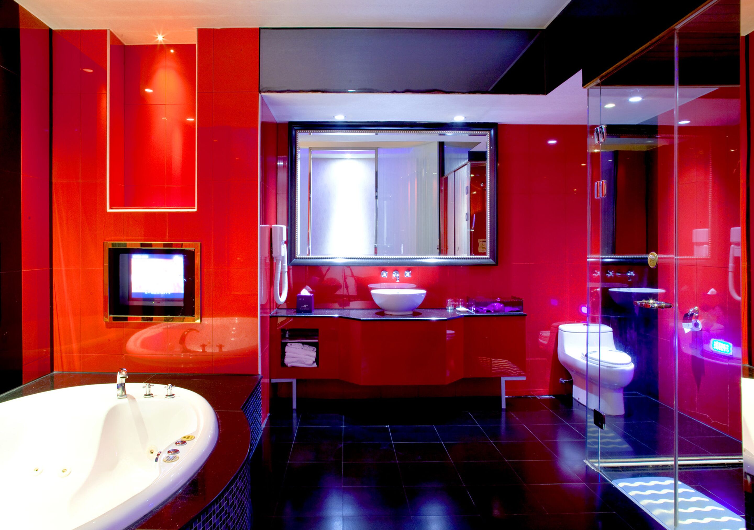 A modern bathroom with a large bathtub, a glass-enclosed shower, and a red color scheme.