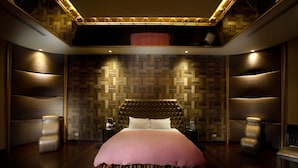 Ein luxuriöses Schlafzimmer mit einem großen Bett, bequemen Sitzgelegenheiten und einer Wand mit Muster.