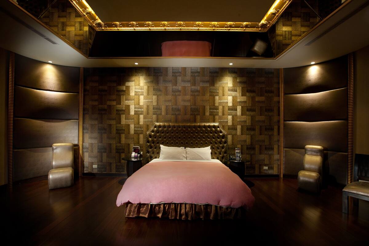 Ein luxuriöses Schlafzimmer mit einem großen Bett, bequemen Sitzgelegenheiten und einer Wand mit Muster.
