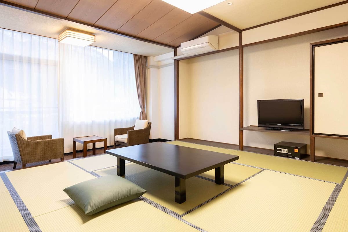 Ett traditionellt japanskt rum med tatamimattor på golvet, ett lågt bord, en soffa och en tv.