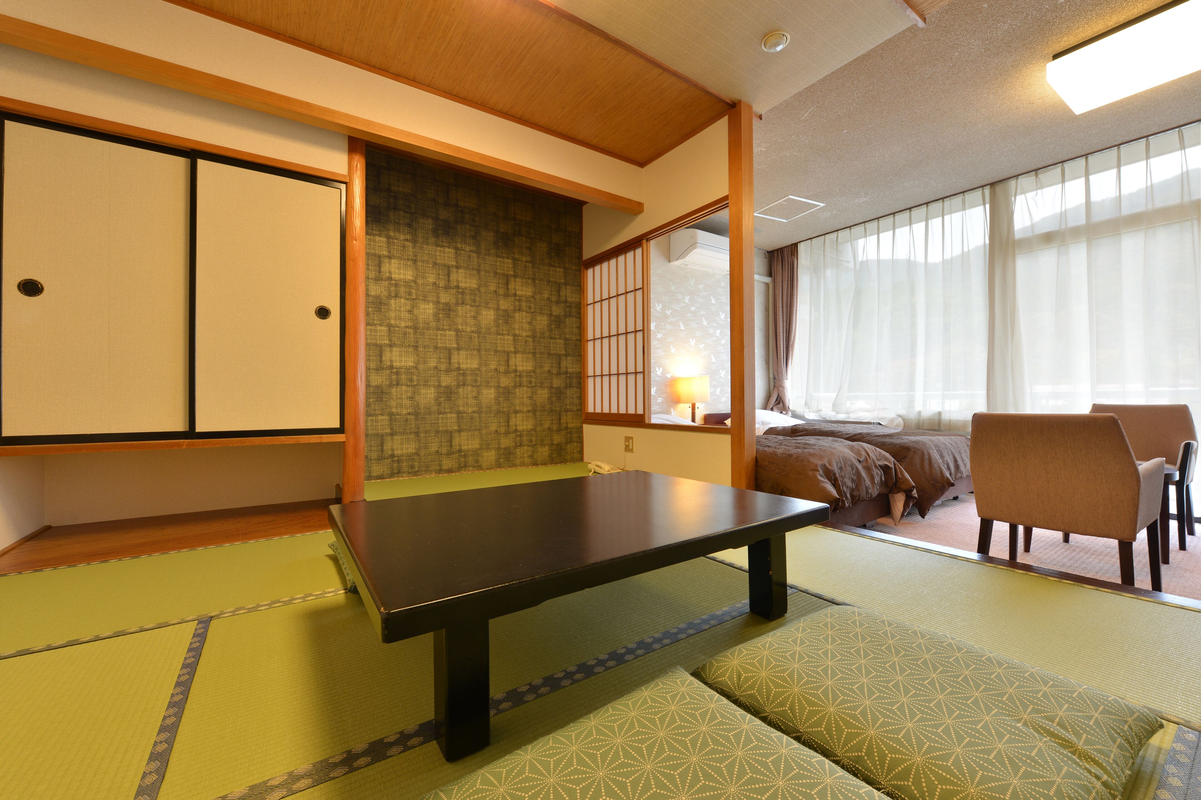 Una habitació japonesa tradicional amb tatami, una taula baixa, un llit amb futó i portes corredisses.