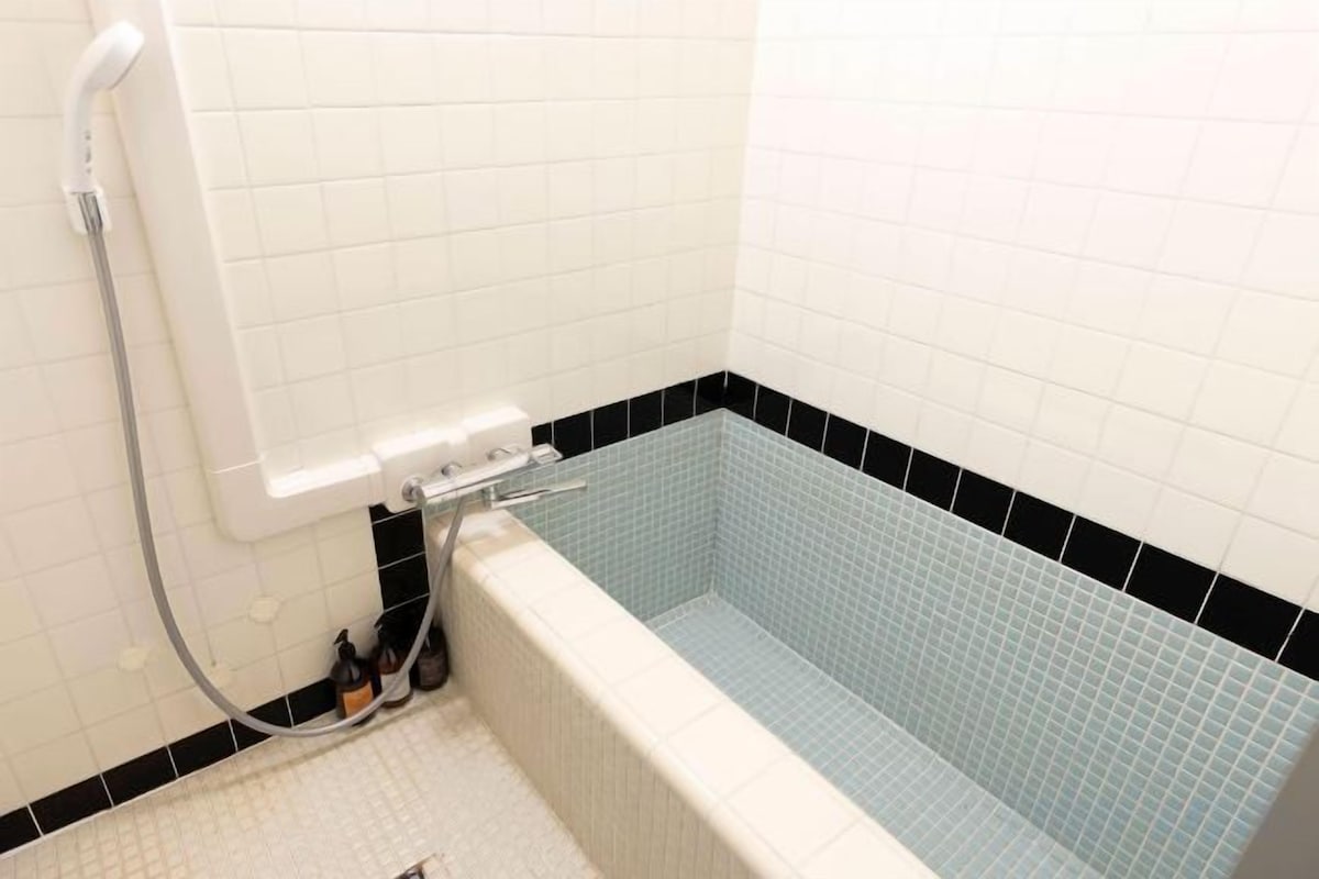 Un baño con bañera, ducha y suelo de baldosas.