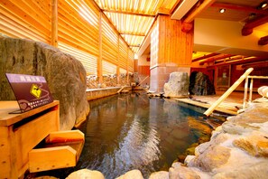 A hot spring area with wooden beams and stone walls.