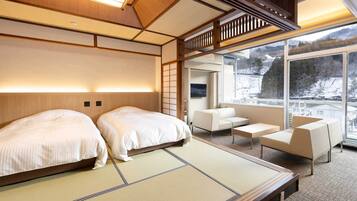 A hotel room with two beds, a sofa, and a view of a snowy landscape.