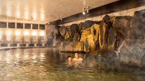 Un área de aguas termales interiores con una pared rocosa y varios bancos.