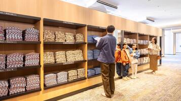A clothing store with shelves labeled by size and gender, and a group of people browsing.