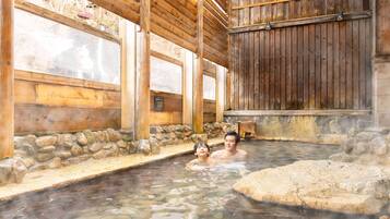 A traditional wooden bathhouse with stone walls and a wooden ceiling.