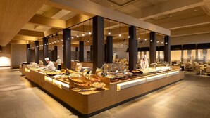 Montaje de bufé con múltiples estaciones de comida, personal atendiendo y un diseño de interiores moderno.