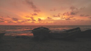 Vene rannalla, taustalla auringonlasku.
