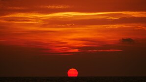 Kirkkaan taivaan alla auringonlasku valtameren yllä.
