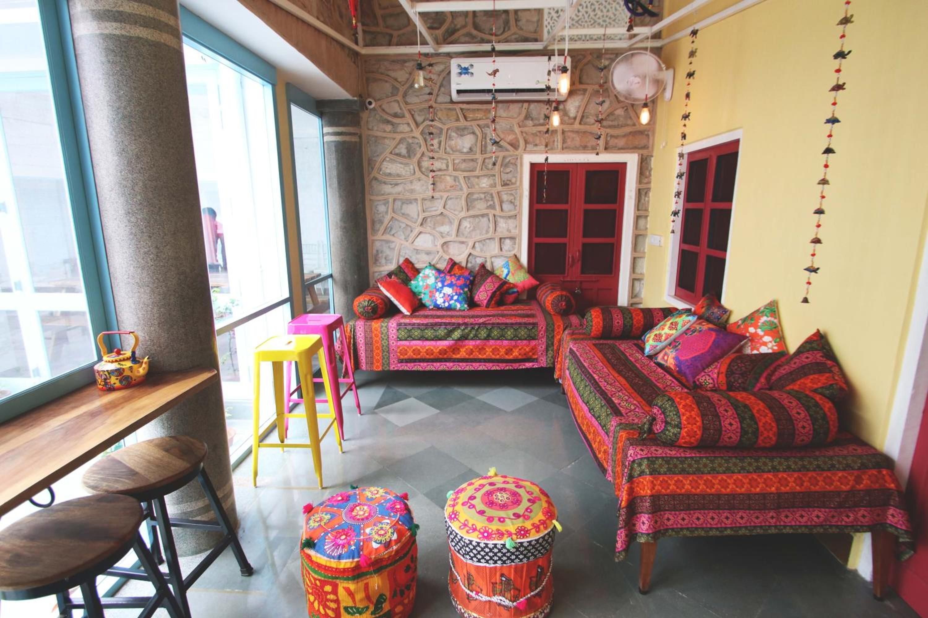 A cozy room with a stone wall, a wooden bench, a colorful sofa, and a small stool.