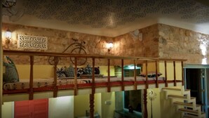 A room with a stone wall, a wooden staircase, and a bed with a patterned bedspread. - Jaipur Jantar Hostel (Jaipur)