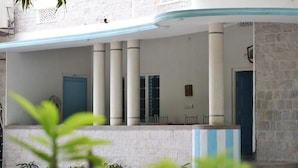 A building with a white exterior, blue doors, and columns. There are plants in the foreground. - Jaipur Jantar Hostel (Jaipur)