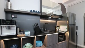 Una cocina moderna con microondas integrado, cafetera y refrigerador de acero inoxidable.