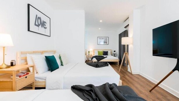 A hotel room with two beds, a TV, a desk, and a framed 'LOVE' sign on the wall. - My Hotel Herrity (Bangkok)