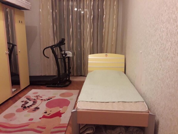 A small bedroom with a single bed, a wardrobe, and an exercise machine.
