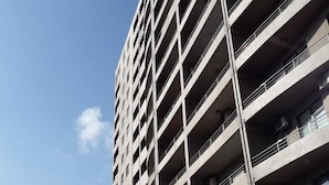 Un parking à étages doté d’une architecture moderne, avec une série de balcons et un logo en forme de couronne bien visible sur la façade.