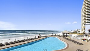 Une piscine avec des chaises longues et vue sur la plage.