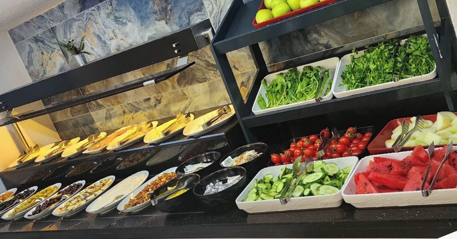 A buffet with various food items including fruits, vegetables, and salads.