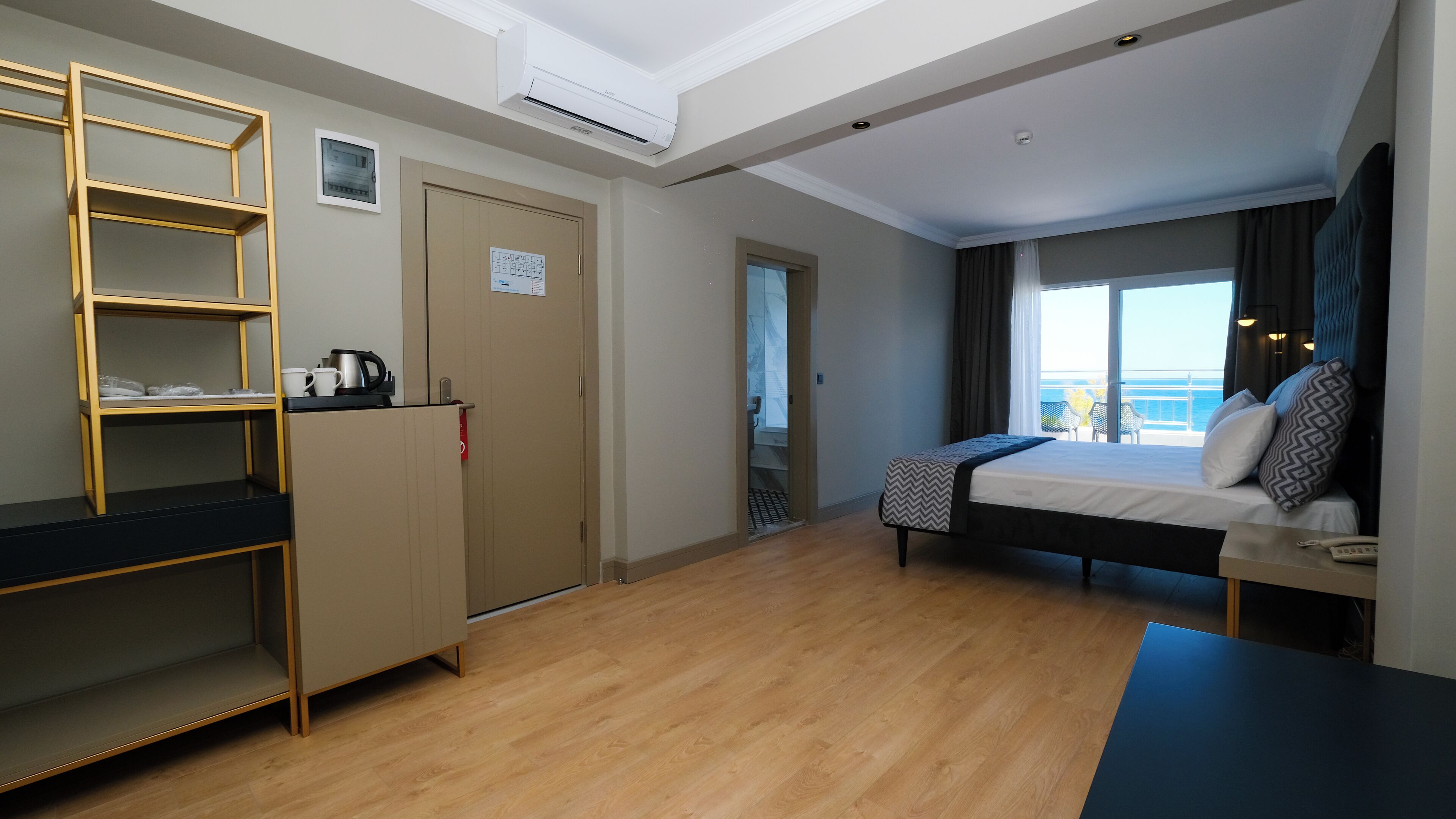 Una habitación de hotel con cama, escritorio, armario y vista al mar.