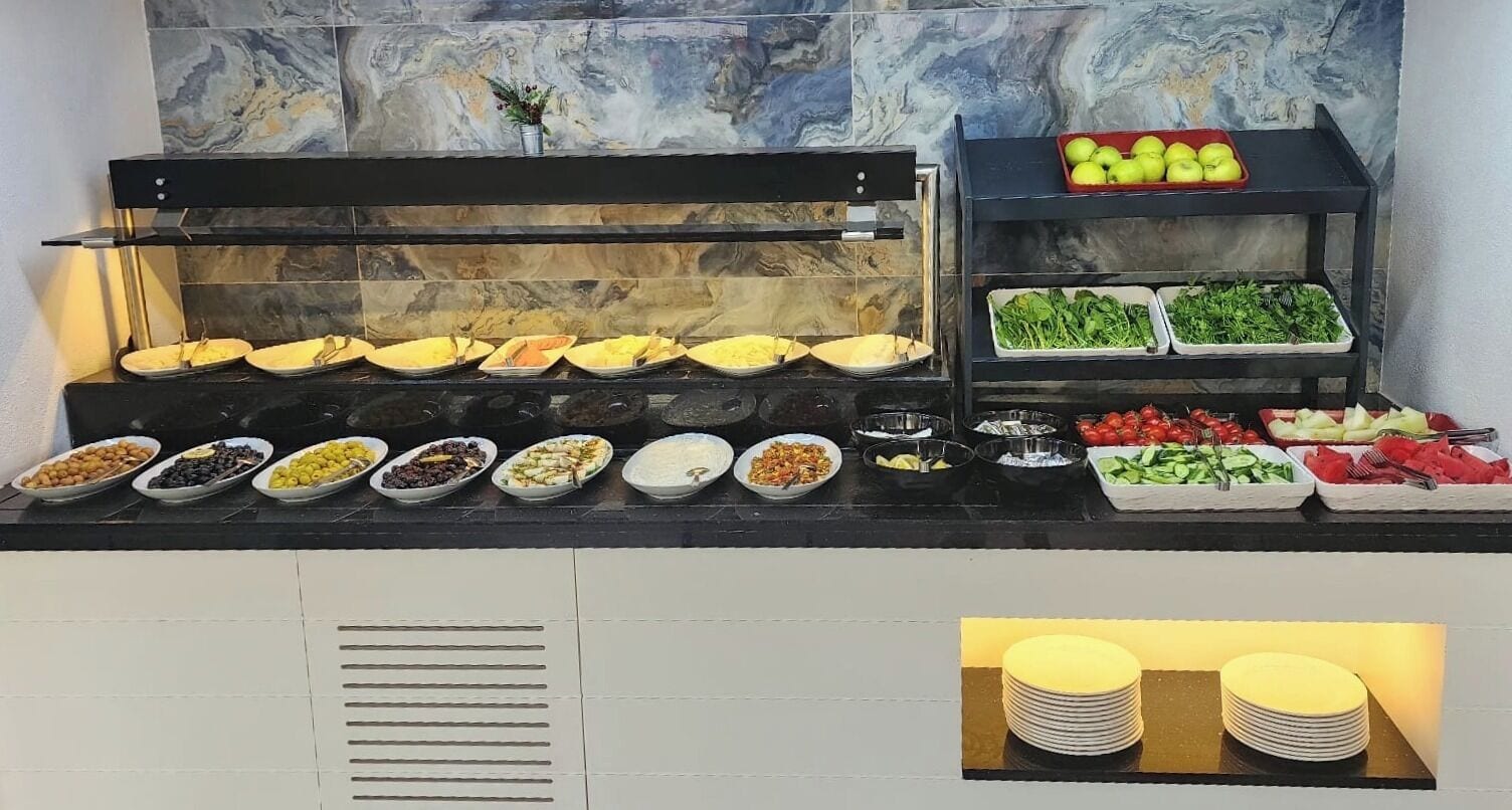 A buffet with various food items and a marble wall in the background.