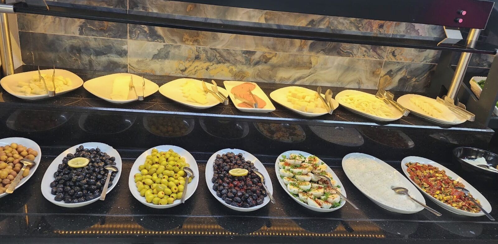 Un bufé con diversos platos, incluyendo frutas, verduras y comidas preparadas.