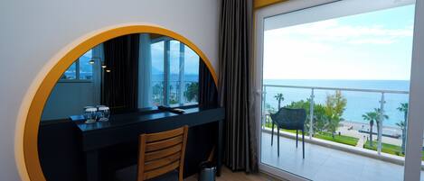 A modern room with a circular window, a desk, a chair, and a view of the sea.